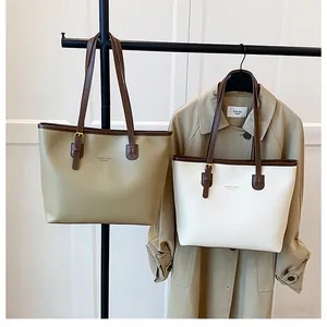 Detailed close-up of khaki and cream tote bags with leather straps and gold buckle accents