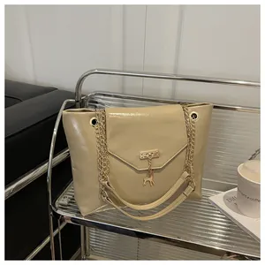 Close-up of khaki faux leather handbag with gold deer charm and elegant chain strap