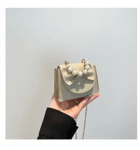 Detailed macro view of the cream-white litchi grain bag with elegant bow and pearl handle