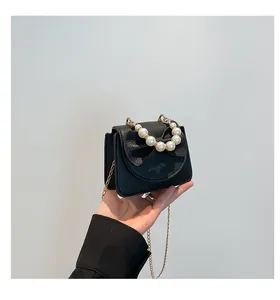 Detail of black mini crossbody bag with pearl handle and leather bow decoration