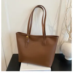 Detailed view of dark brown tote bag with gold lettering and adjustable buckle strap