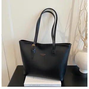 Macro view of minimalist black leather tote bag featuring gold lettering on white books