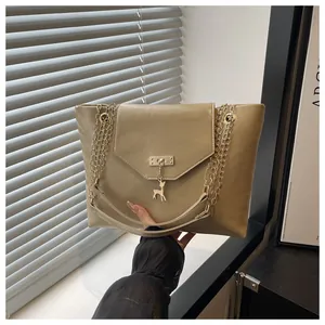 Detail of beige faux leather handbag featuring a golden deer charm and chain strap