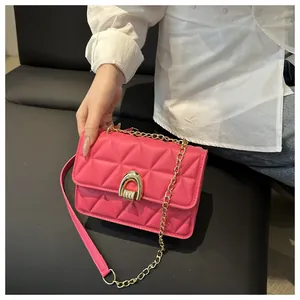 Détail d'un sac à main matelassé rose vif avec fermoir doré et bandoulière en chaîne