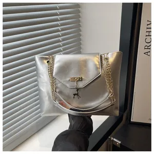 Detail of silver metallic handbag with gold deer pendant and chain shoulder strap