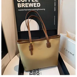 Detailed view of khaki large tote bag with brown contrast straps in a luxury gift box