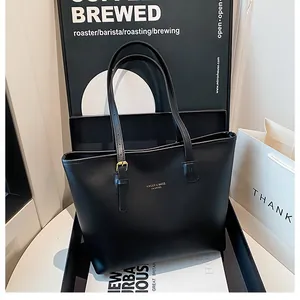 Detail shot of black faux leather tote bag featuring gold hardware and logo branding