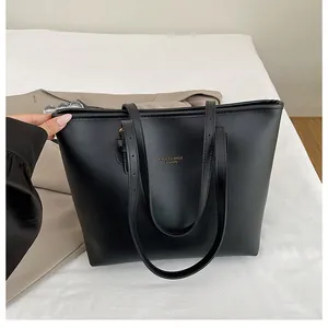 Close-up of black matte tote bag with golden XMDFR brand lettering and leather texture