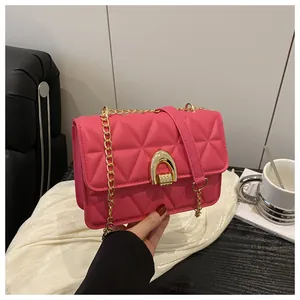 Détail d'un sac en cuir matelassé rose avec boucle en U dorée et bandoulière chaîne