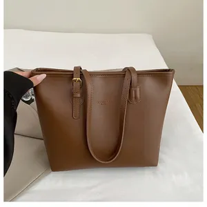 Detail of brown PU leather tote bag with adjustable gold buckle and debossed text
