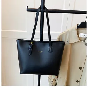 Detail of black tote bag featuring gold lettering and adjustable shoulder strap buckle