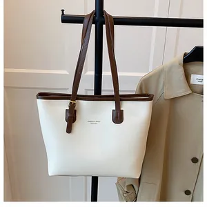 Detail view of cream tote bag with dark brown trim and elegant lettering print
