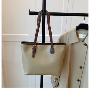Detailed view of large olive green tote bag with brown trim and metal strap buckle