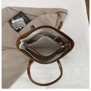 Internal view of brown tote bag showing multi-layer compartments and gold zipper