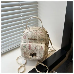 Detail of the woven floral texture with cartoon prints and metal turn-lock on the mini bag