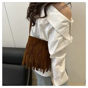 Sac bandoulière en daim marron à longues franges porté par un mannequin au décor épuré