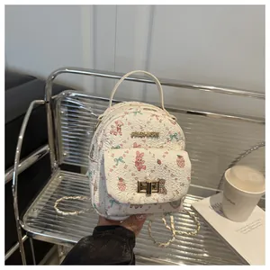 Detail view of mini white backpack featuring floral cartoon prints and gold hardware accents