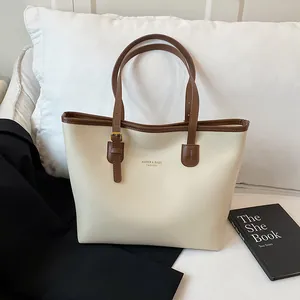 Minimalist beige tote bag with brown leather handles and large capacity design