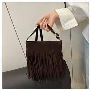 Détail d'un sac bandoulière en daim marron foncé avec de longues franges et boucle réglable