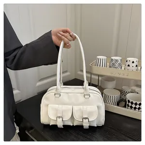 Détail du sac boston en cuir verni blanc avec deux poches à boucle et de longues anses