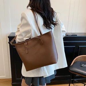 Deep brown leather tote bag with gold logo and long shoulder strap for office commuting