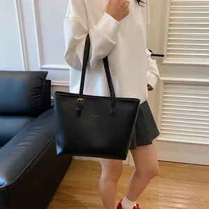 Classic black leather tote bag with gold logo and long straps for versatile daily commute