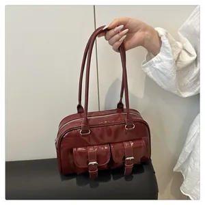 Détail du sac en cuir brillant bordeaux avec poches à rabat et boucles argentées