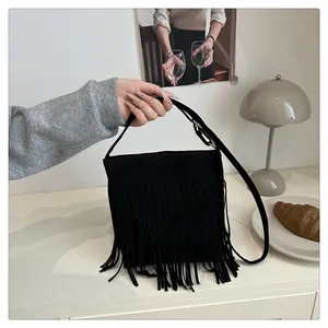 Détail du sac à bandoulière en daim noir avec franges denses et sangle plate