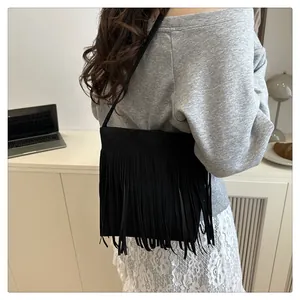 Sac à bandoulière noir à franges tendance présenté dans un décor lifestyle avec mannequin