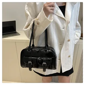 Détail du sac à bandoulière noir brillant avec deux poches à rabat et boucles argentées