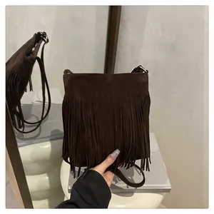 Détail du sac bandoulière en daim marron foncé avec de longues franges style bohème