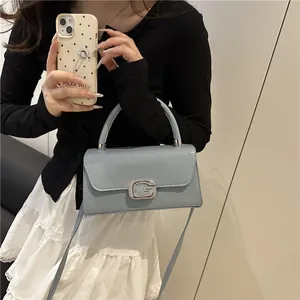 Elegant light blue glossy patent leather square bag with diamond G buckle on a model