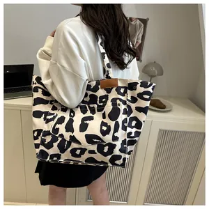 Detail view of canvas leopard print tote bag with brown leather trim and metal rivets