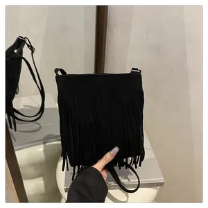 Détail d'un sac à main noir en daim avec de longues franges et une fine bandoulière réglable