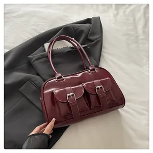 Détail du sac bowling en cuir verni bordeaux avec poches avant sur une veste