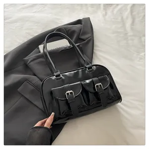Détail du sac à main en cuir verni noir avec deux poches avant et boucles argentées
