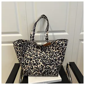 Detailed view of leopard print tote bag with brown leather label on a metal chair