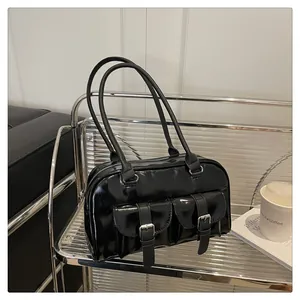 Détail d'un sac en cuir verni noir brillant avec boucles argentées sur étagère métal