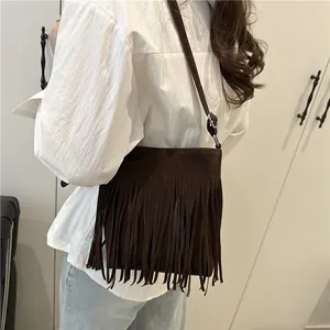 Sac bandoulière marron à franges en daim synthétique porté par un mannequin