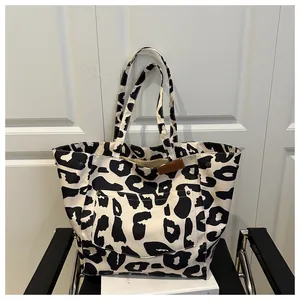 Detail of leopard print canvas tote bag with large outer pocket and leather tag