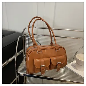 Détail du sac à bandoulière en cuir verni marron brillant avec deux poches à boucle argentée
