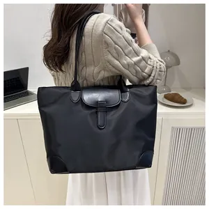 Model wearing a black nylon tote bag with leather trim in a modern office workplace setting