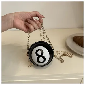 Close-up of a circular black billiard 8-ball crossbody bag with gold chain and zipper