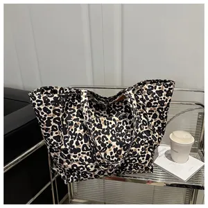 Detail of a large leopard print canvas tote bag with front pocket and wide shoulder strap