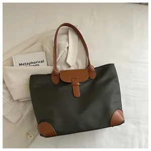 Detail of green nylon tote bag with brown leather accents and magnetic buckle closure