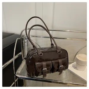 Détail du sac en cuir verni marron foncé avec poches doubles et boucles argentées