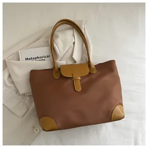 Detail of color-block tote bag with coffee nylon fabric and mustard leather handles