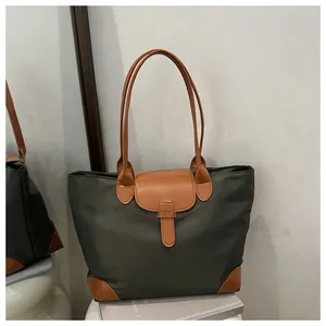 Detail view of dark green tote bag with brown leather corners and contrast stitching