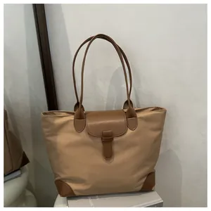 Close-up of contrast leather trim and stitching on khaki nylon tote bag detail