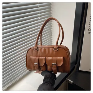 Détail du sac vintage en cuir marron caramel avec boucles argentées et poches avant